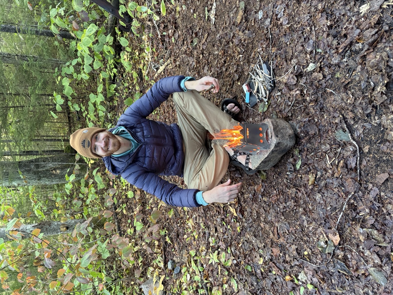 James tending a small twig stove at a backcountry campsite in the White Mountains