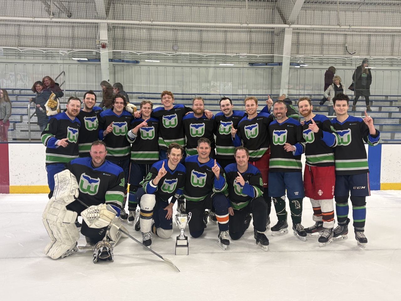 James with his rec hockey team on the ice, celebrating with a championship trophy